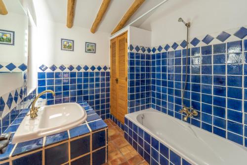 baño de azulejos azules con bañera y lavamanos en Vivienda Rural Las Bartolas en Jaén