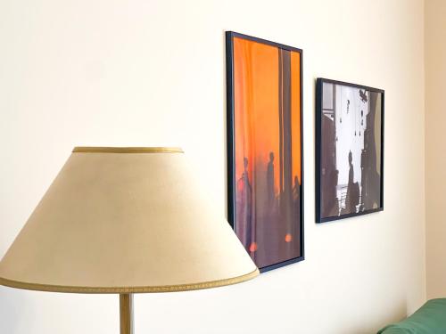 um candeeiro num quarto com duas fotografias na parede em Skyline Sunset City Center em Tirana