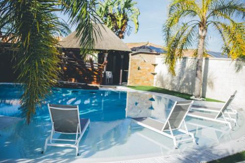 two chairs and a swimming pool with palm trees at Villa Campito in El Puerto de Santa María