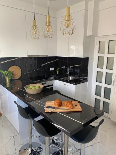 eine Küche mit einer schwarzen Theke mit Croissants auf einem Schneidebrett in der Unterkunft Kolonaki 1 bedroom and 1 Sofabed Amazing Penthouse flat in Athen