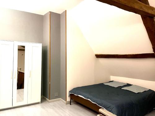 Schlafzimmer mit einem Bett und einem Spiegel in der Unterkunft Chablis: grand studio en plein centre ville in Chablis
