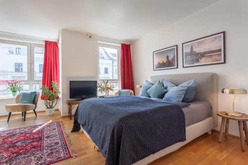 a bedroom with a bed and a television and red curtains at Stilvolles Studio in downtown Mitte, Boxspringbett, Balkon, Blick über Berlin auf den Himmel, zentrale Lage, Kiez vor der Haustür in Berlin