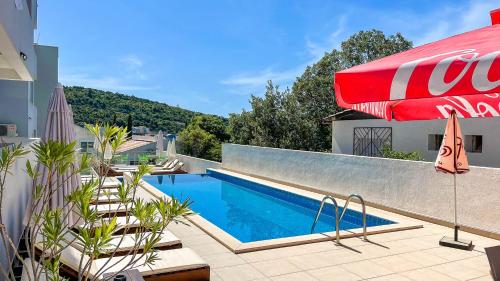 una piscina con una sombrilla roja junto a un edificio en Apartments Limunada, en Utjeha