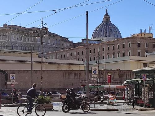Ein Mann, der Motorrad fährt auf einer Stadtstraße mit einem Gebäude in der Unterkunft Locazione turistica di Via Ottaviano a Roma in Rom