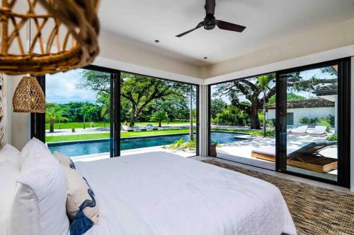 a bedroom with a large white bed and a pool at Villa Twilight Tree 5Bdr Nature & Exclusivity in San José Pinilla