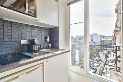 une cuisine avec un évier et une grande fenêtre dans l'établissement Cosy and New Studio in the Heart of Paris (5F), à Paris