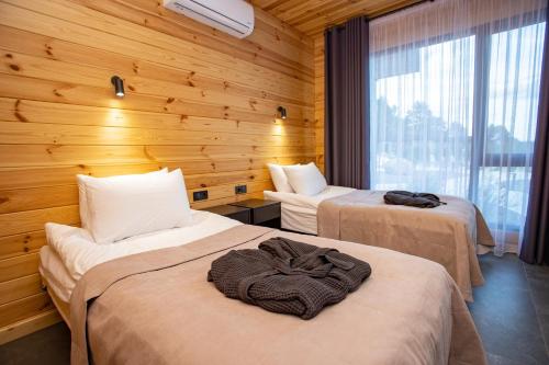 two beds in a room with wooden walls at Perlyna Resort in Cherkasy