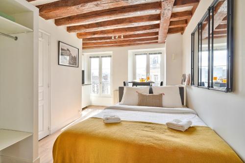 - une chambre avec un grand lit dans une pièce dotée de fenêtres dans l'établissement Cosy and New Studio in the Heart of Paris (5F), à Paris