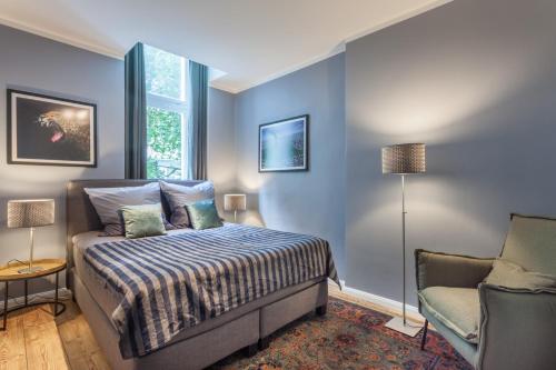 a bedroom with blue walls and a bed and a chair at The Paul II - stylish & central 3 BR apartment, group & family friendly, 4- 6 Guests in Berlin