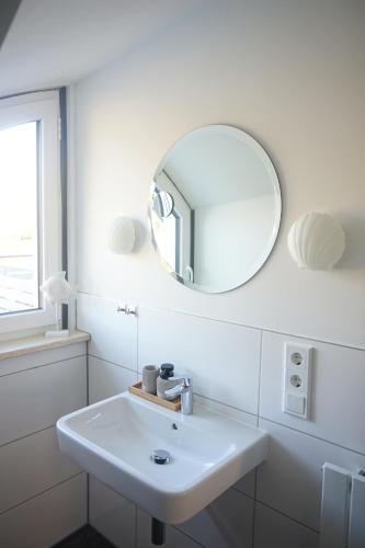 a white bathroom with a sink and a mirror at Landhotel Strandallee in Wunstorf