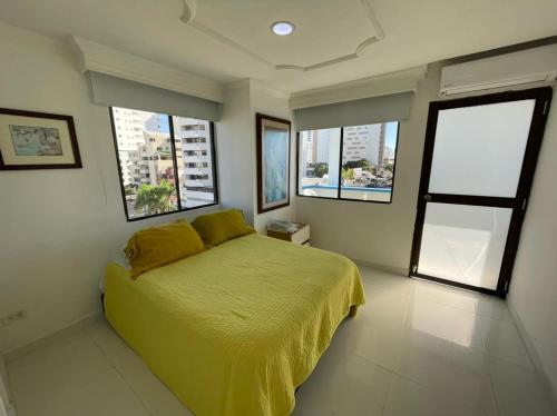 a bedroom with a bed with yellow sheets and windows at Vista Al Mar, Aire Acondicionado en Todo el Apto, Wi-Fi, Parqueadero in Cartagena de Indias
