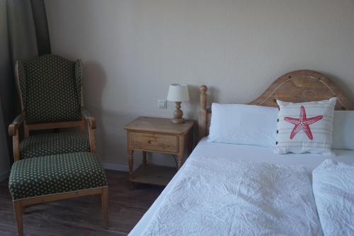a bedroom with a bed with a starfish pillow and a chair at Landhotel Strandallee in Wunstorf