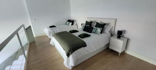 1 dormitorio con 2 camas blancas y suelo de madera en The Green Loft - Wifi, Parking Privado en Camarma de Esteruelas