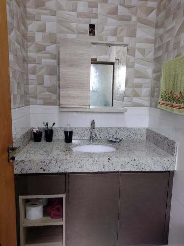 a bathroom counter with a sink and a mirror at Sobrado Praia Nova Tramandaí in Tramandaí