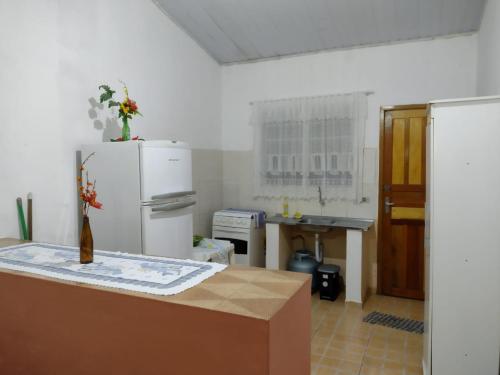 a kitchen with a white refrigerator and a table at Casa da Voh in Ilha Comprida