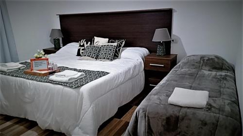 1 dormitorio con 1 cama blanca grande y cabecero en Complejo San Antonio en Fiambala
