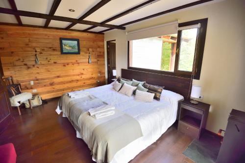 1 dormitorio con 1 cama grande y pared de madera en Le Fario Lodge in Patagonia en Lago Futalaufquen