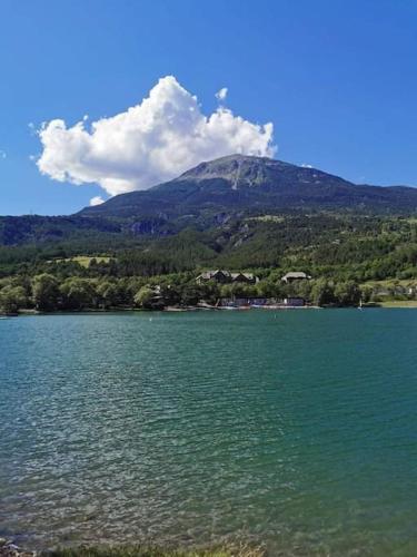 une montagne au loin avec une grande étendue d'eau dans l'établissement Duplex cocooning avec vue lac et montagnes, à Savines