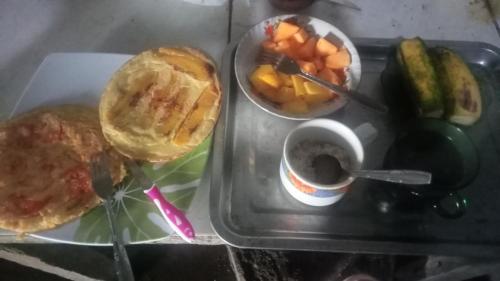 uma bandeja com uma sanduíche e uma chávena de café e fruta em Bukit Senaru Homestay em Senaru