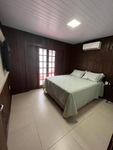 - une chambre avec un lit dans une pièce dotée de murs en bois dans l'établissement Casa Aconchegante com Privacidade em Balneário Rincão, à Aliatar