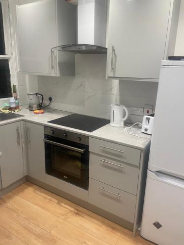 a kitchen with white cabinets and a stove top oven at Beautiful loft with En-Suit in a family house, in London