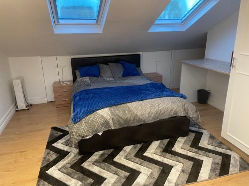 a bedroom with a bed with a blue comforter and a rug at Spacious loft space with private en-suite bathroom in London