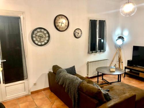 a living room with clocks on the wall and a couch at Domaine Plan des Devens in Roussillon