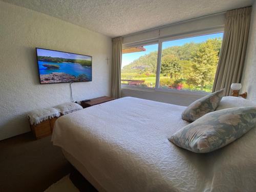 a bedroom with a bed and a large window at La Poza Pucon, a pasos de todo in Pucón
