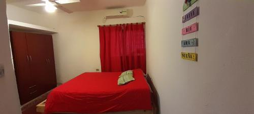Habitación con cama roja y cortina roja en Diaz Deptos en La Rioja