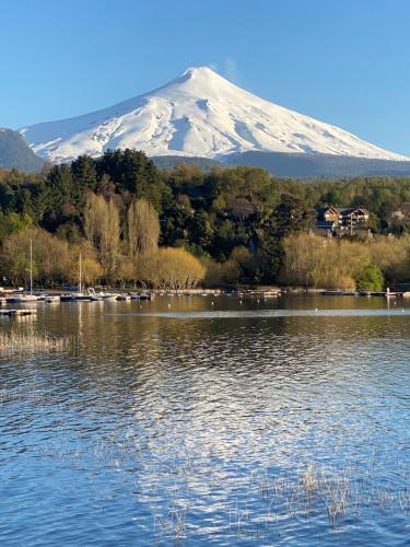 a snow covered mountain sitting next to a body of water at La Poza Pucon, a pasos de todo in Pucón