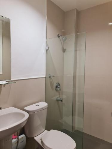 a bathroom with a toilet and a glass shower at Grace & RB Hotel in Kalibo