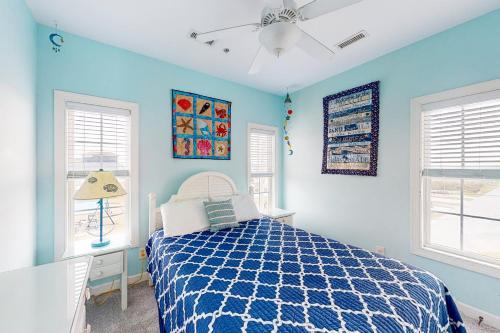 a blue bedroom with a bed and two windows at Moonswept in Surf City
