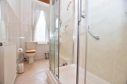 a white bathroom with a shower and a toilet at Lovely flat overlooking the Clyde in Gourock