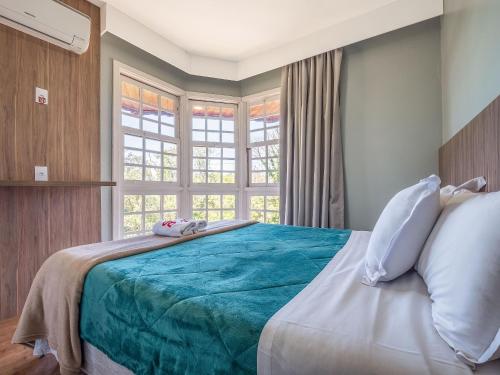 1 dormitorio con 1 cama grande y ventana en Vista Real 102 - Apartamento à 4 minutos da Rua Coberta de Gramado, en Gramado