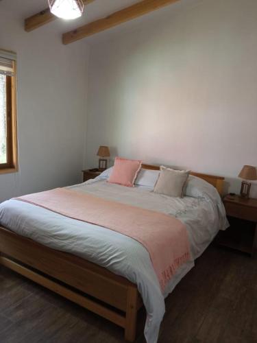 a bedroom with a large bed with two pink pillows at Cabaña "El Gringo" in Coñaripe