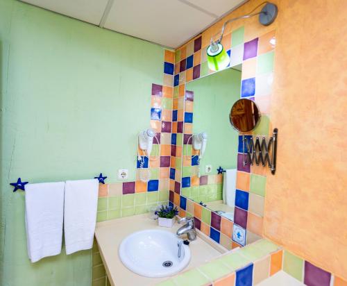 a bathroom with a sink and a mirror at Apartahotel La Espadaña in Rota