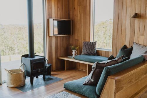 a living room with a couch and a stove at Upland Farm Luxury Cabins, Denmark Western Australia in Denmark