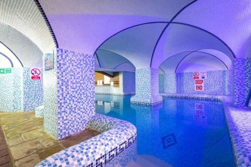 a swimming pool in a room with purple lighting at Coghurst Hall Holiday Home Sleeps 6, 2 bedrooms in Hastings