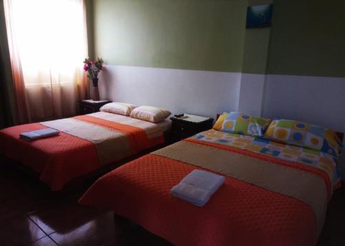 2 camas en una habitación con ventana en Stefany Hospedaje, en Puerto Ayora