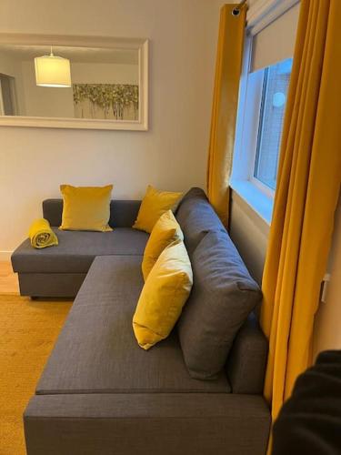 a blue couch with yellow pillows in a living room at Glenbervie - Beautifully refurbished, self-contained apartment in Fife