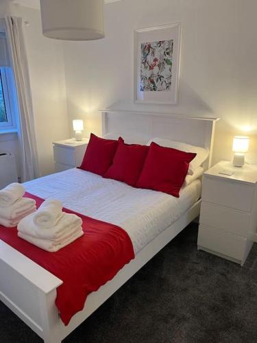 a bedroom with a bed with red pillows and two tables at Beautiful refurbished, self-contained apartment in Fife