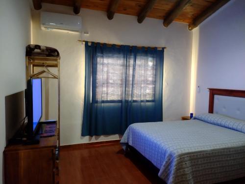 una camera con letto, TV e finestra di Cabaña San Rafael Flor de Loto a San Rafael
