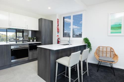 a kitchen with a counter and two stools at The Cove 303 in Forster
