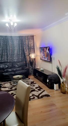 uma sala de estar com um sofá e uma televisão de ecrã plano em 2 Bedroom Apartment - Greater London em Dagenham