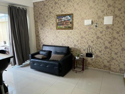 ein Wohnzimmer mit schwarzem Ledersofa und Tapete in der Unterkunft Apartamento Só Alegria in Bombinhas