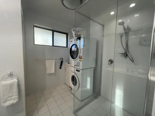 a bathroom with a washing machine and a glass shower at The Sandy Villa 150 meters from Sawtell Beach in Sawtell