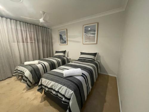 três camas estão alinhadas num quarto em The Sandy Villa 150 meters from Sawtell Beach em Sawtell