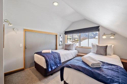 Schlafzimmer im Dachgeschoss mit 2 Betten und einem Fenster in der Unterkunft Lakeside Indulgence on Wilmot in Queenstown