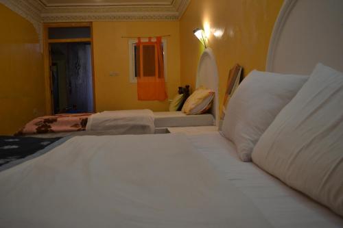 a bedroom with two beds and a room with two beds at Maison D'hote Amazir in Boumalne