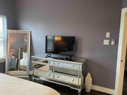 a bedroom with a dresser with a tv and a mirror at Skyline Views with Garage Parking 10 minutes from Downtown, NRG Stadium and Medical CTR in Houston